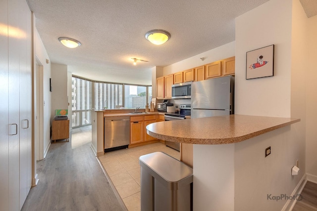 222 N Columbus Dr Unit 912, Chicago, IL 60601 - kitchen with appliances with stainless steel finishes, a peninsula, light wood finished floors, light brown cabinetry, and light countertops