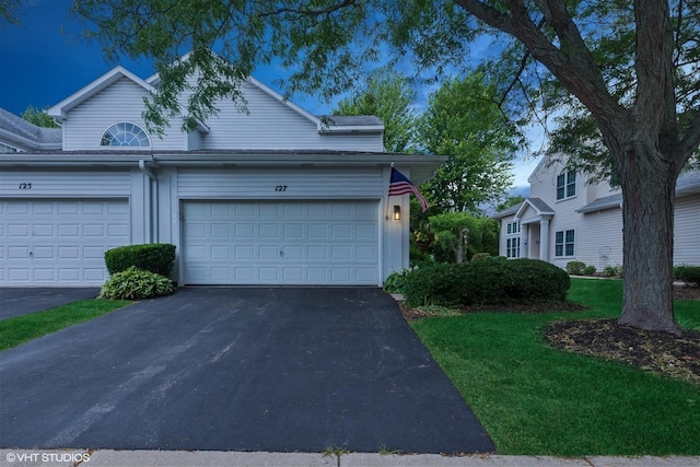 view of front facade with driveway, an attached garage, and a front yard