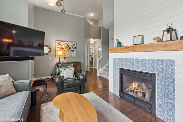 living area with wood finished floors, a towering ceiling, and stairway