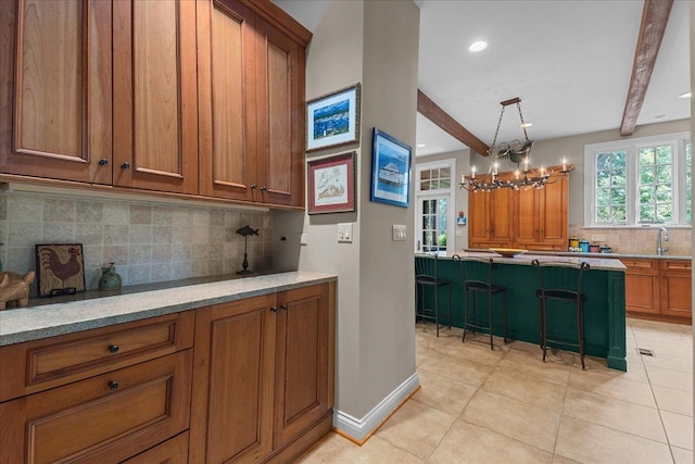 1005 Hiawatha Ln, Riverwoods, IL 60015 - kitchen featuring brown cabinets, backsplash, a kitchen bar, light tile patterned floors, and a chandelier