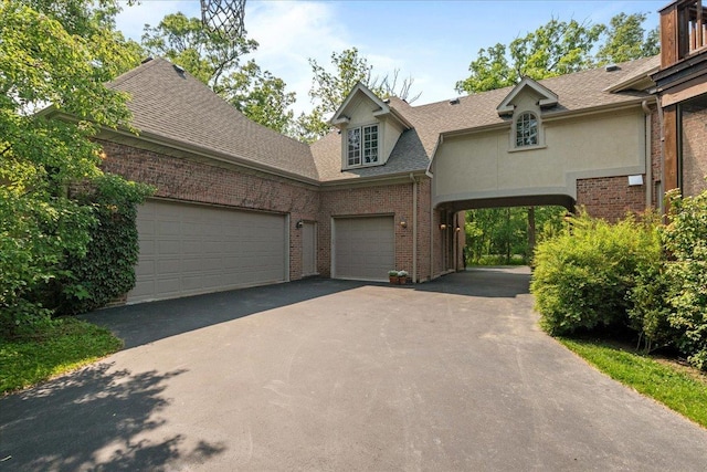 1005 Hiawatha Ln, Riverwoods, IL 60015 - view of front facade featuring driveway, brick siding, roof with shingles, an attached garage, and stucco siding