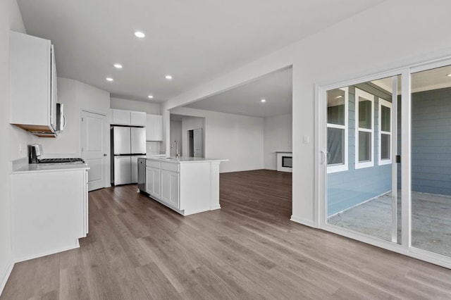 9900 Humbolt St, Huntley, IL 60142 - kitchen with appliances with stainless steel finishes, wood finished floors, white cabinets, an island with sink, and light countertops