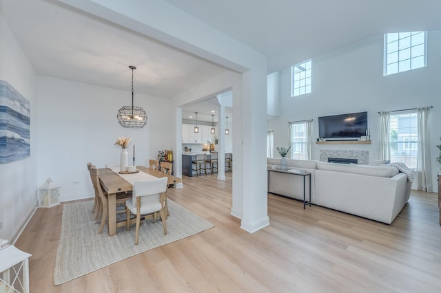 25320 W Alison Rd, Plainfield, IL 60586 - dining area featuring wood finished floors, healthy amount of natural light, a chandelier, a fireplace, and a towering ceiling