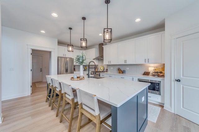 25320 W Alison Rd, Plainfield, IL 60586 - kitchen with stainless steel appliances, wall chimney exhaust hood, light wood finished floors, decorative backsplash, and white cabinets