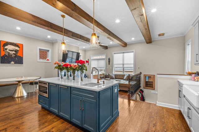 4741 S Drexel Blvd, Chicago, IL 60615 - kitchen featuring blue cabinets, stainless steel microwave, light countertops, dark wood-type flooring, and beam ceiling