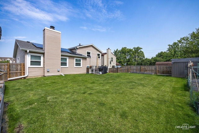 209 Surrey Dr, Carol Stream, IL 60188 - rear view of property with a chimney, a fenced backyard, and roof mounted solar panels