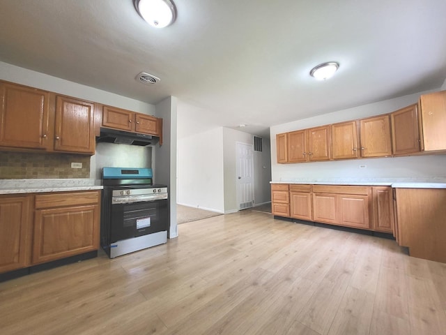 2313 Joppa Ave, Zion, IL 60099 - kitchen featuring stainless steel range with electric stovetop, under cabinet range hood, brown cabinetry, and light countertops