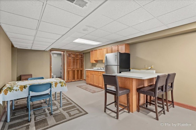 2N445 Beith Rd, Elburn, IL 60119 - kitchen featuring freestanding refrigerator, a breakfast bar, a peninsula, light countertops, and a drop ceiling