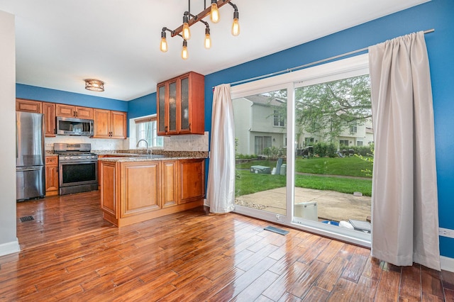 31 E Shagbark Ln, Streamwood, IL 60107 - kitchen with appliances with stainless steel finishes, brown cabinetry, backsplash, and dark wood-style flooring