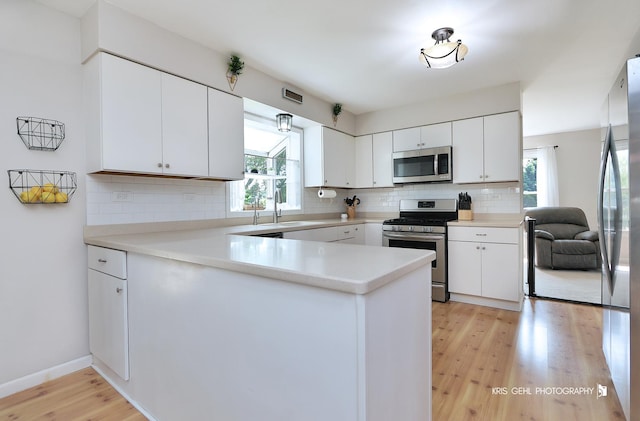 21136 W Engle Dr, Lake Villa, IL 60046 - kitchen with appliances with stainless steel finishes, tasteful backsplash, light wood finished floors, a peninsula, and white cabinets