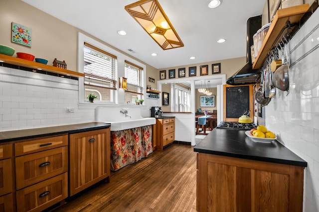 7439 N Maplewood Ave, Chicago, IL 60645 - kitchen with open shelves, brown cabinets, dark countertops, dark wood finished floors, and tasteful backsplash
