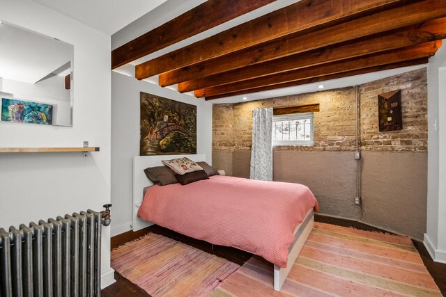 7439 N Maplewood Ave, Chicago, IL 60645 - bedroom with radiator heating unit, beamed ceiling, wood finished floors, and brick wall