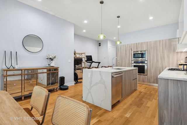 5236 N Kenmore Ave Unit 1N, Chicago, IL 60640 - kitchen featuring appliances with stainless steel finishes, modern cabinets, a center island with sink, light wood-type flooring, and light stone counters