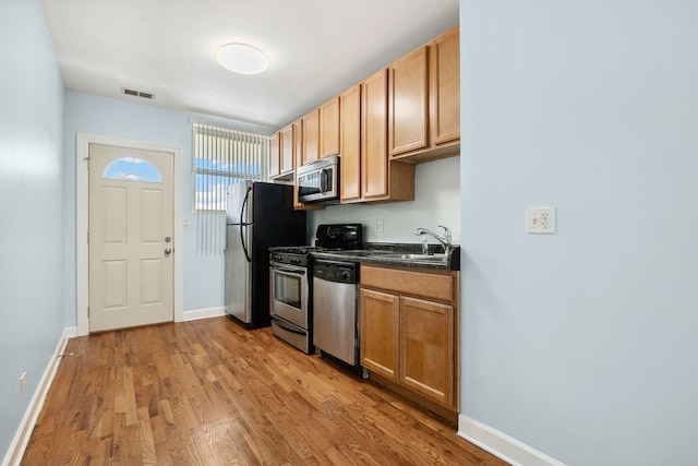 2554 W Rosemont Ave Unit 3, Chicago, IL 60659 - kitchen featuring appliances with stainless steel finishes, light wood-style flooring, and dark countertops