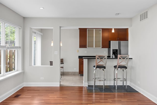 905 Huntington Dr, Elk Grove Village, IL 60007 - kitchen with stainless steel refrigerator with ice dispenser, a kitchen breakfast bar, wood finished floors, dark countertops, and recessed lighting