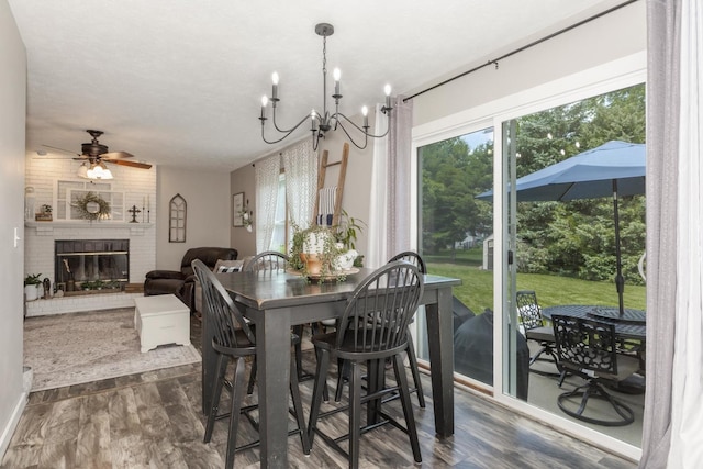 1608 Surrey St, Normal, IL 61761 - dining room featuring dark wood-style flooring, a ceiling fan, a chandelier, and a brick fireplace
