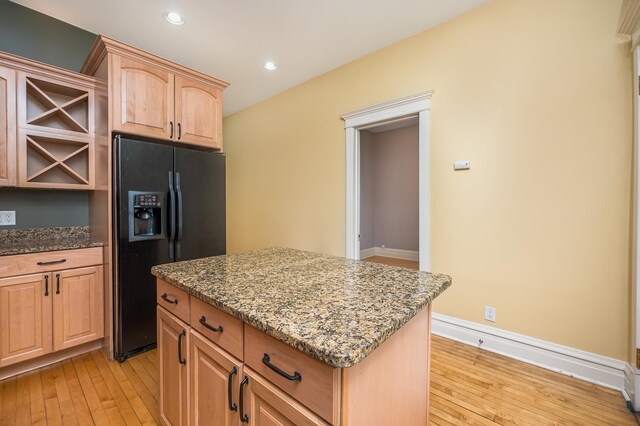 2115 N Sawyer Ave, Chicago, IL 60647 - kitchen with black fridge, light wood-style flooring, light stone countertops, light brown cabinets, and a kitchen island