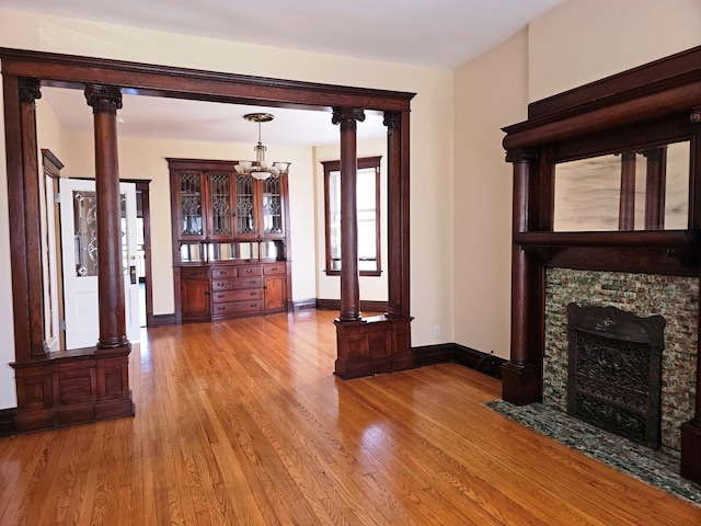 2115 N Sawyer Ave, Chicago, IL 60647 - unfurnished living room featuring a chandelier, wood finished floors, and a stone fireplace