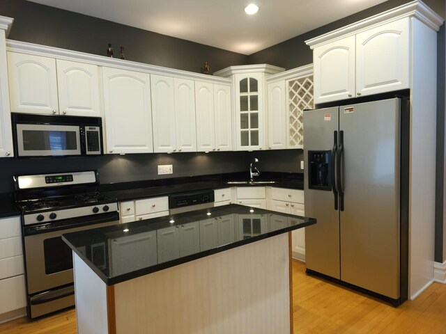 2115 N Sawyer Ave, Chicago, IL 60647 - kitchen with appliances with stainless steel finishes, light wood-style floors, white cabinetry, a center island, and glass insert cabinets