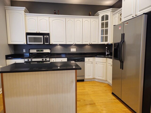 2115 N Sawyer Ave, Chicago, IL 60647 - kitchen featuring stainless steel appliances, light wood finished floors, dark countertops, white cabinets, and glass insert cabinets