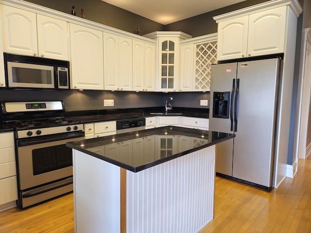 2115 N Sawyer Ave, Chicago, IL 60647 - kitchen with stainless steel appliances, light wood-style floors, glass insert cabinets, a center island, and white cabinets