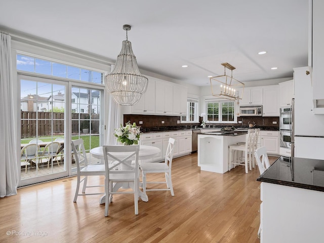 551 W 3rd St, Elmhurst, IL 60126 - kitchen featuring stainless steel appliances, a chandelier, white cabinetry, decorative backsplash, and light wood-type flooring