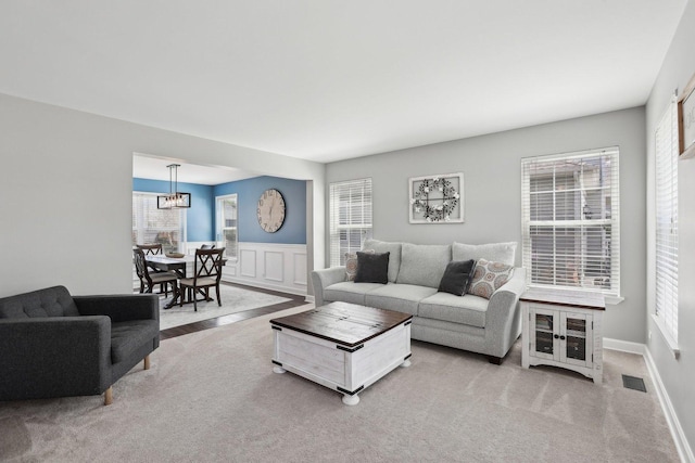 11176 Fleetwood St, Huntley, IL 60142 - carpeted living room featuring a chandelier, wainscoting, and a decorative wall