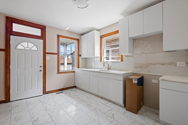 5407 S Justine St, Chicago, IL 60609 - kitchen with light countertops, light marble finish floors, white cabinets, and backsplash