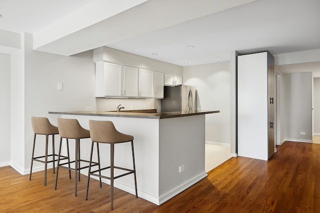 40 E 9th St Unit 1609, Chicago, IL 60605 - kitchen with freestanding refrigerator, dark countertops, a peninsula, white cabinetry, and a kitchen bar