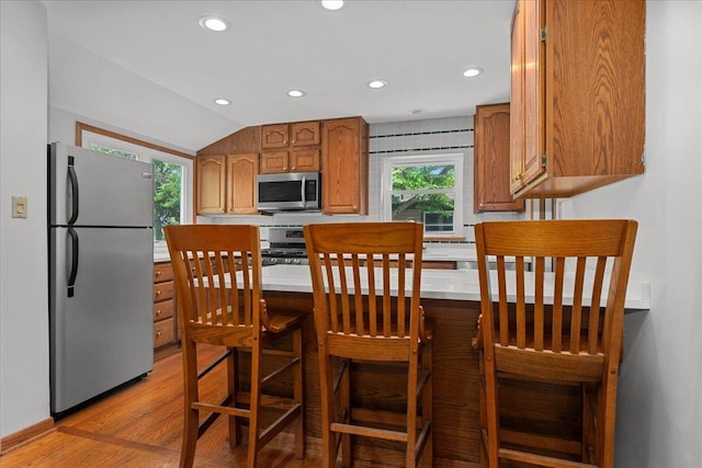 1719 Ferndale Ave, Northbrook, IL 60062 - kitchen featuring stainless steel appliances, brown cabinets, lofted ceiling, recessed lighting, and light wood-type flooring