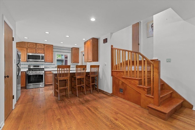 1719 Ferndale Ave, Northbrook, IL 60062 - kitchen with appliances with stainless steel finishes, light wood-type flooring, brown cabinets, recessed lighting, and a peninsula