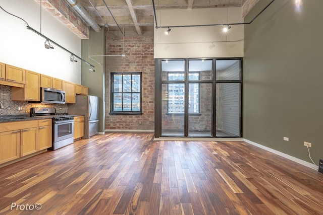 20 N State St Unit 1012, Chicago, IL 60602 - kitchen featuring stainless steel appliances, a high ceiling, dark countertops, dark wood-type flooring, and rail lighting