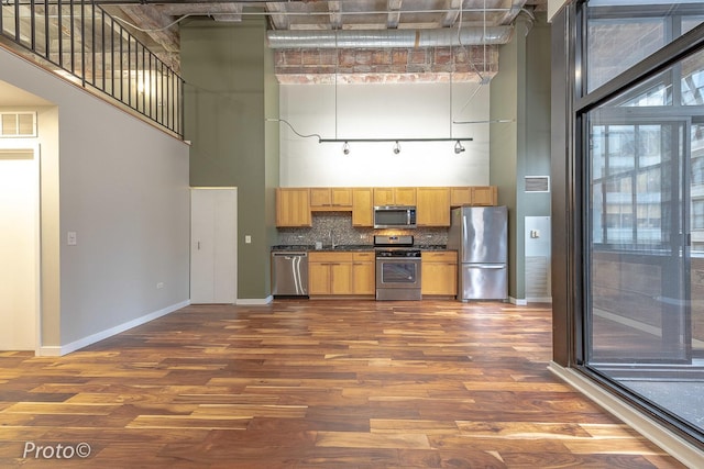 20 N State St Unit 1012, Chicago, IL 60602 - kitchen featuring appliances with stainless steel finishes, a towering ceiling, dark countertops, dark wood-style floors, and tasteful backsplash