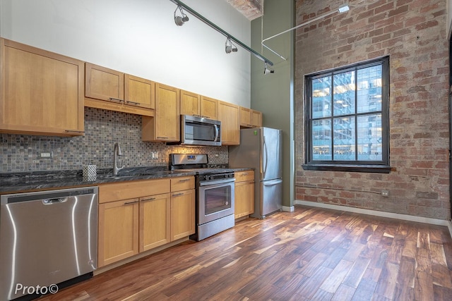 20 N State St Unit 1012, Chicago, IL 60602 - kitchen featuring stainless steel appliances, a towering ceiling, decorative backsplash, dark wood-style flooring, and dark stone counters