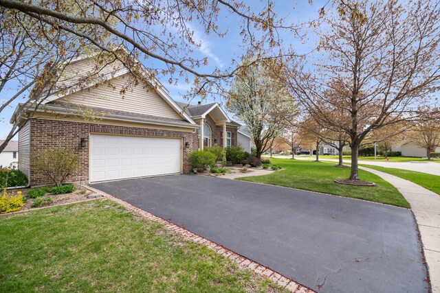 145 Barnes Rd, Elgin, IL 60124 - view of front of house featuring brick siding, asphalt driveway, an attached garage, and a front lawn
