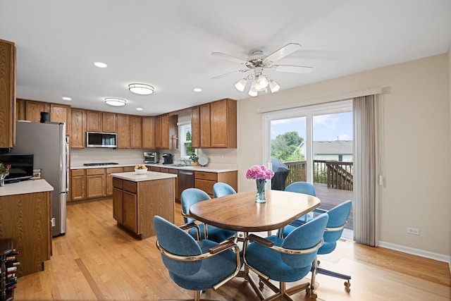 145 Barnes Rd, Elgin, IL 60124 - kitchen featuring stainless steel appliances, brown cabinetry, light wood-style floors, a center island, and light countertops
