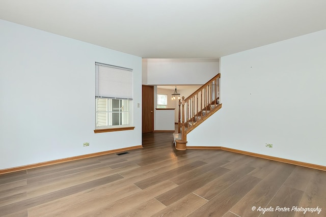179 Cascade Dr, Crystal Lake, IL 60012 - spare room featuring stairway, wood finished floors, and a chandelier