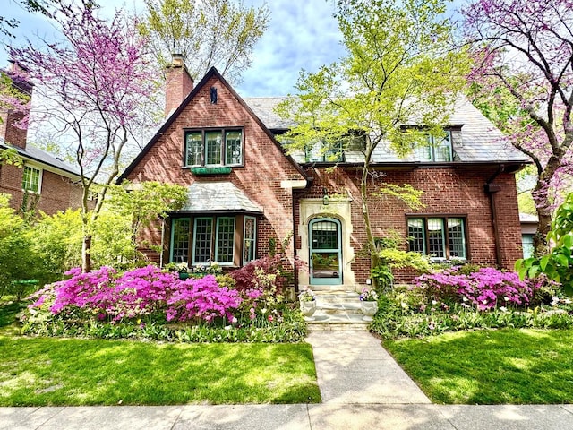 2951 Colfax St, Evanston, IL 60201 - tudor home featuring a chimney, a front yard, and brick siding