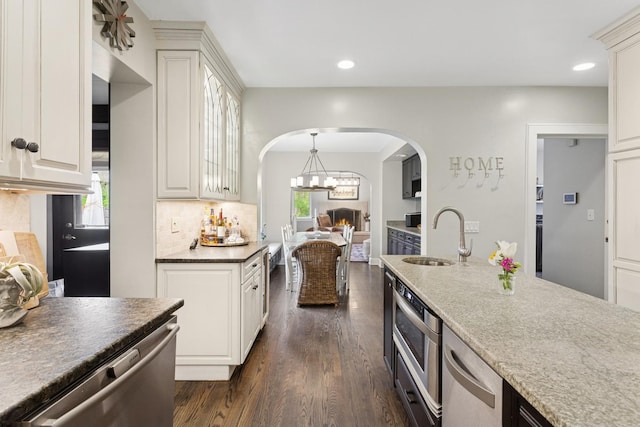 2951 Colfax St, Evanston, IL 60201 - kitchen featuring appliances with stainless steel finishes, arched walkways, decorative backsplash, dark wood-style floors, and a sink
