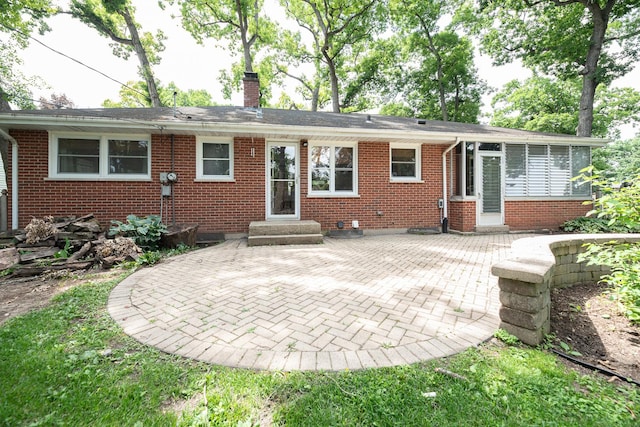 308 Dunbar Rd, Mundelein, IL 60060 - back of house with a chimney, a patio, brick siding, a sunroom, and entry steps