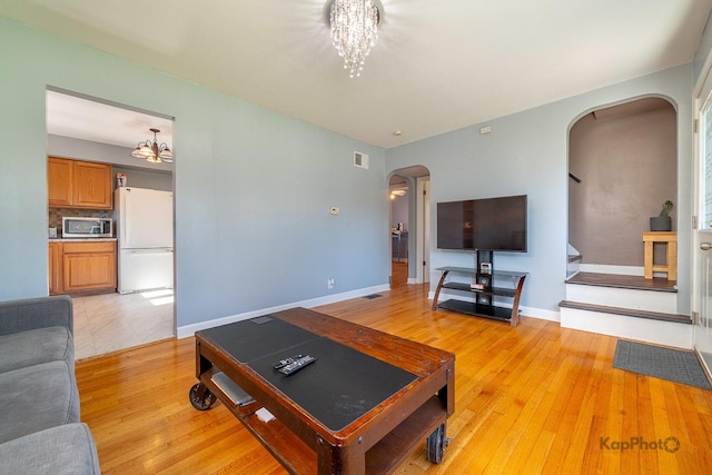 7828 Suburban Ln, Bridgeview, IL 60455 - living room featuring arched walkways, a chandelier, and light wood-style flooring