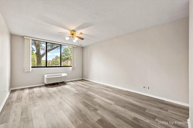 2000 Saint Regis Dr Unit 1D, Lombard, IL 60148 - empty room with a wall mounted air conditioner, ceiling fan, wood finished floors, and a textured ceiling