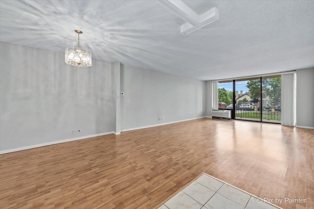 2000 Saint Regis Dr Unit 1D, Lombard, IL 60148 - empty room with floor to ceiling windows, wood finished floors, a textured ceiling, a chandelier, and a wall unit AC
