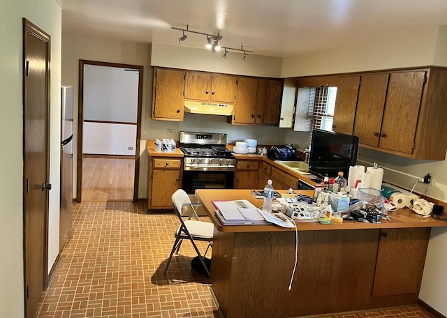 3485 Ronald Rd, Crete, IL 60417 - kitchen with stainless steel range with gas stovetop, under cabinet range hood, a peninsula, and brown cabinetry