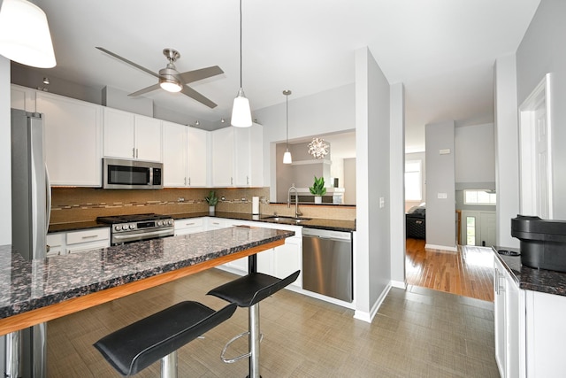 2208 W Concord Ln, Addison, IL 60101 - kitchen featuring stainless steel appliances, a breakfast bar, decorative backsplash, ceiling fan, and white cabinetry
