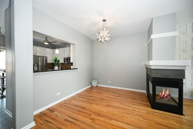 2208 W Concord Ln, Addison, IL 60101 - unfurnished living room with light wood-style flooring, a chandelier, a tiled fireplace, and ceiling fan