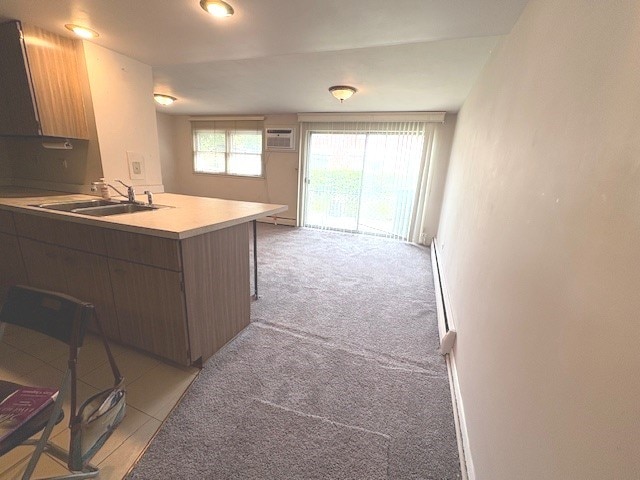 8801 Robin Dr Unit C, Des Plaines, IL 60016 - kitchen featuring a peninsula, light countertops, light colored carpet, a wall mounted AC, and modern cabinets