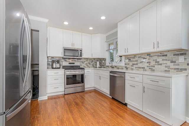 1910 Heather Ln, Joliet, IL 60431 - kitchen featuring stainless steel appliances, light countertops, light wood-style floors, decorative backsplash, and white cabinets