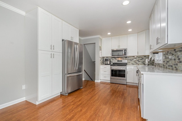 1910 Heather Ln, Joliet, IL 60431 - kitchen featuring appliances with stainless steel finishes, ornamental molding, light countertops, tasteful backsplash, and light wood-type flooring