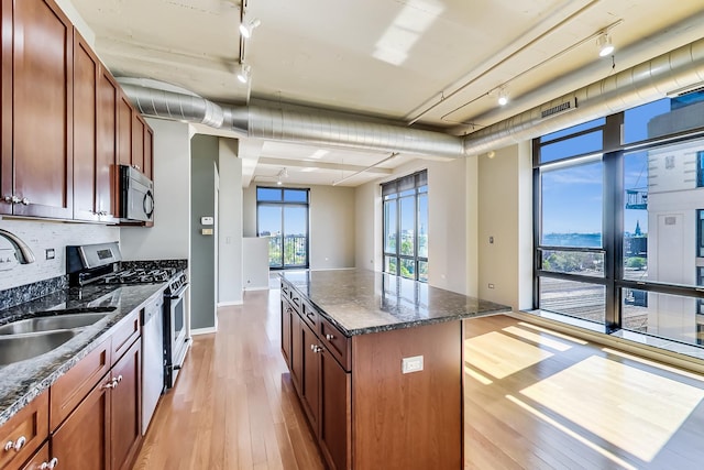 1525 S Sangamon St Unit 609, Chicago, IL 60608 - kitchen featuring appliances with stainless steel finishes, track lighting, light wood-style floors, a kitchen island, and decorative backsplash